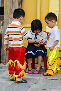 Three Vietnamese children in costume waiting to go on stage.