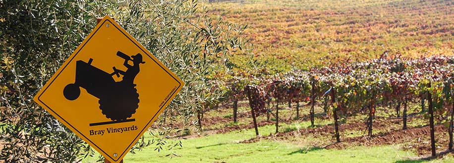 Local Plymouth, California wine country sign showing a farmer drinking wine while driving a tractor.